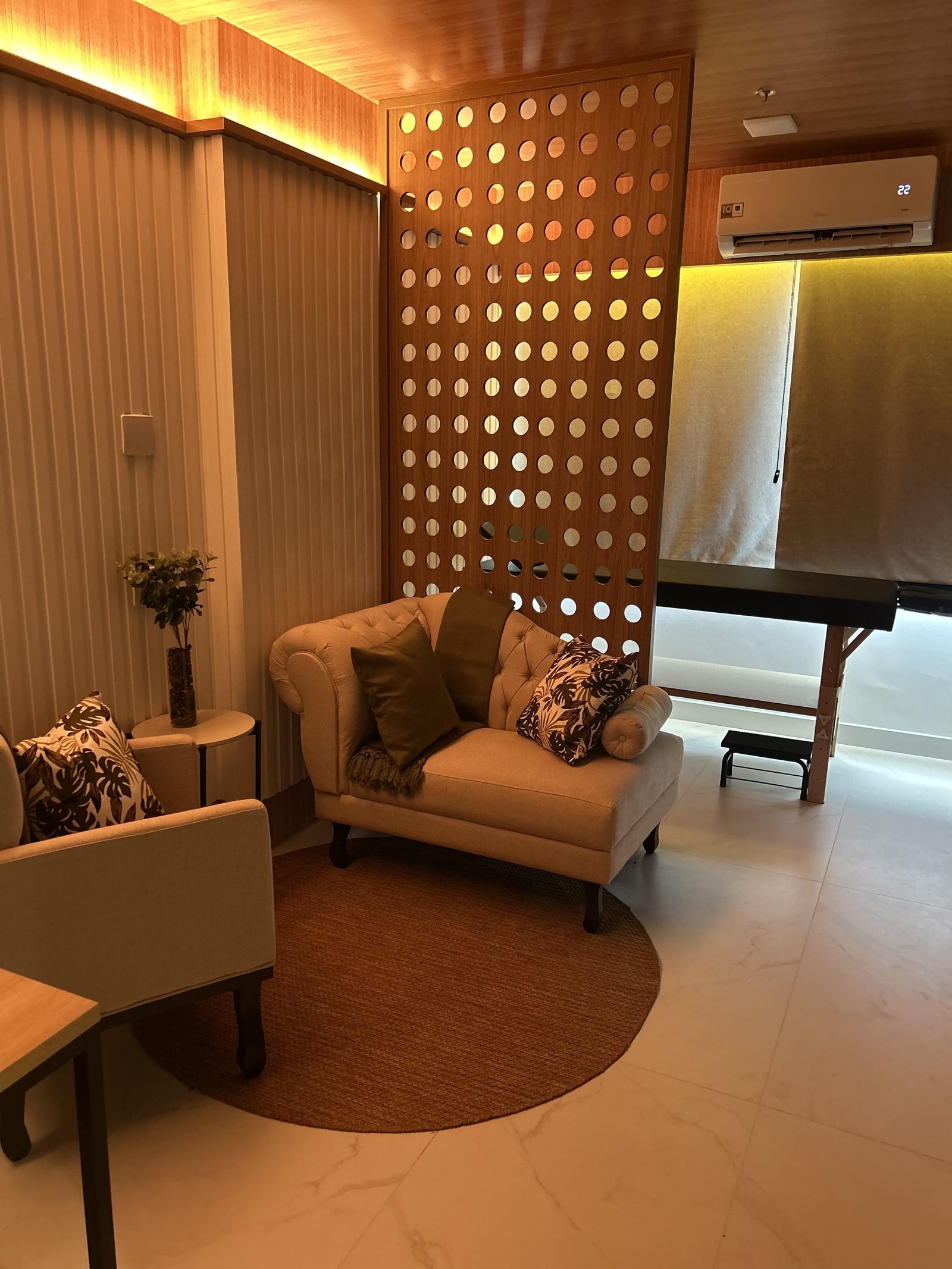 Sala de espera com cobogó de madeira iluminado e poltrona chesterfield
