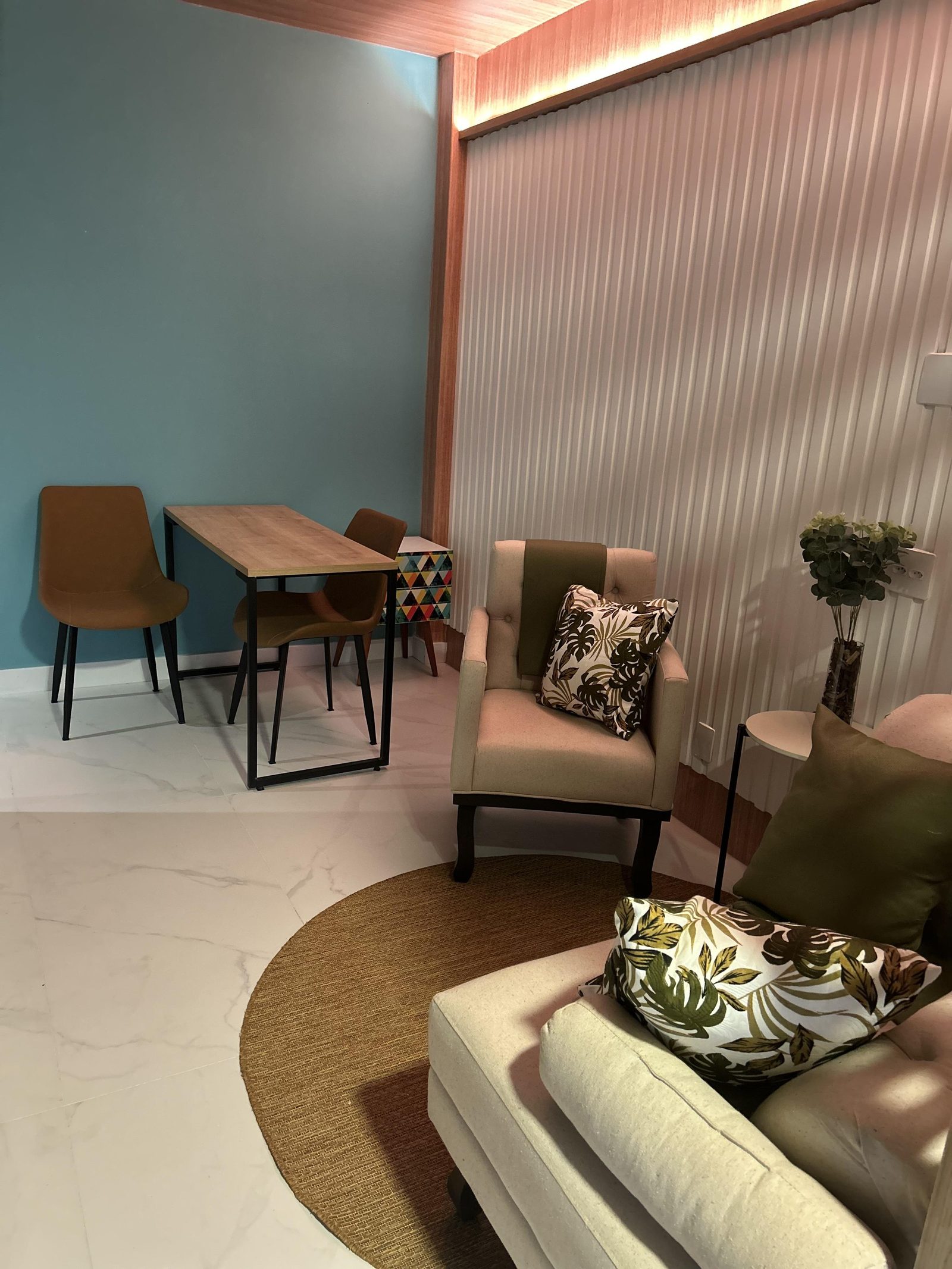 Ambiente de recepção com parede azul, mesa de madeira e poltronas